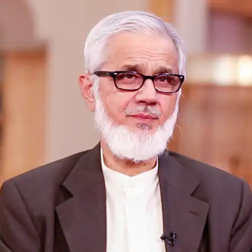 An older Middle Eastern man with white hair and beard in a blazer over a cleric's shirt.