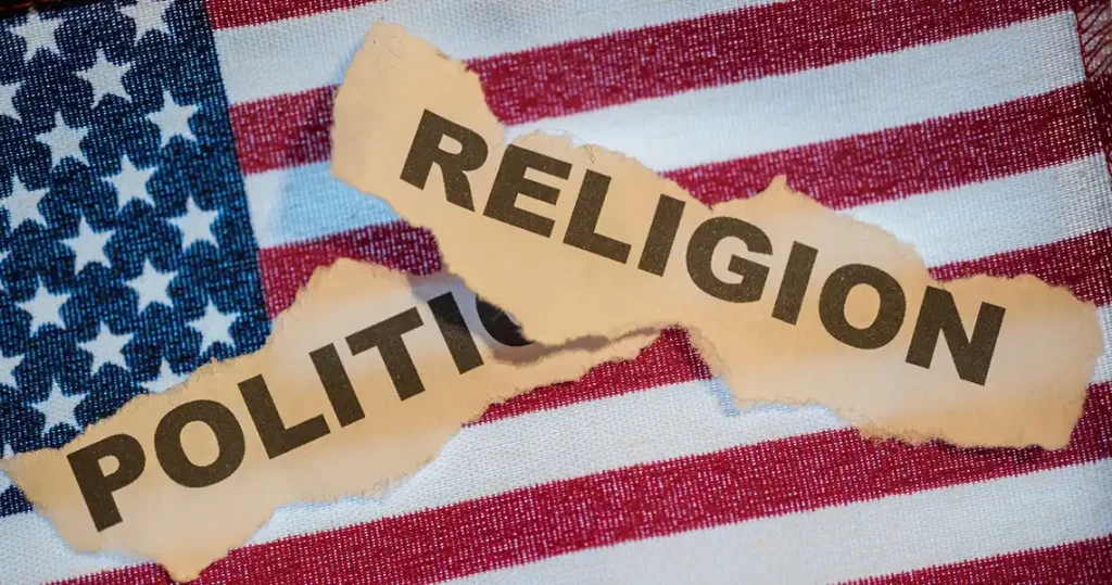 US flag with the words politics and religion printed on separate pieces of paper that's been torn out and laid on the flag
