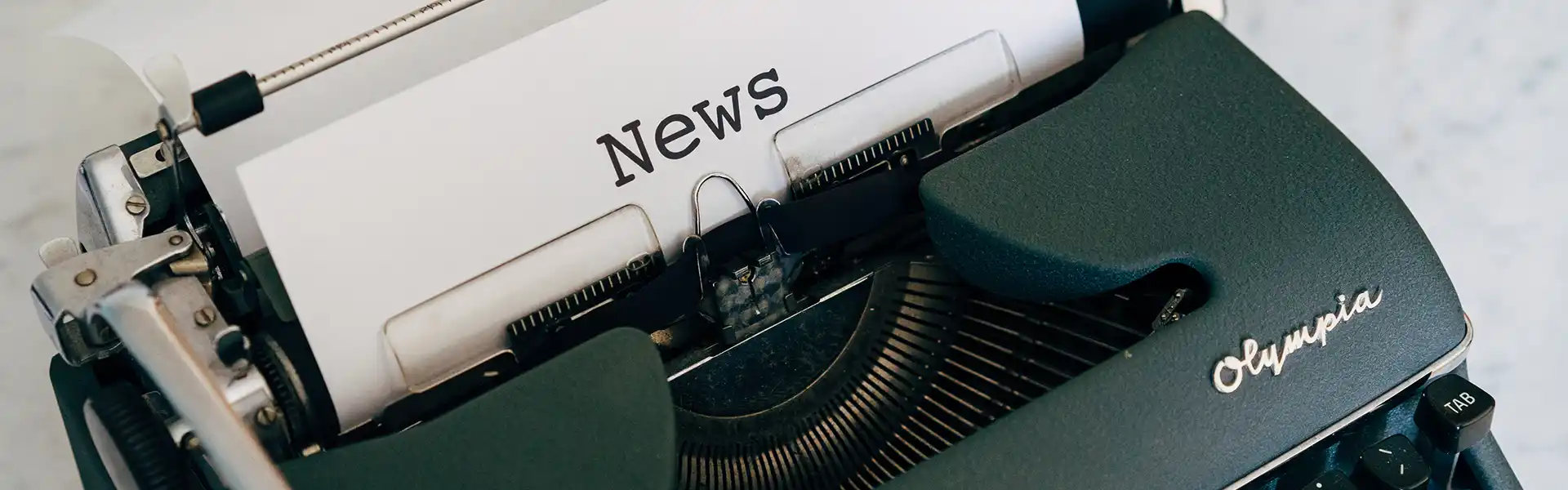 Close-up of an old manual typewriter with a sheet of paper coming out the top which reads News
